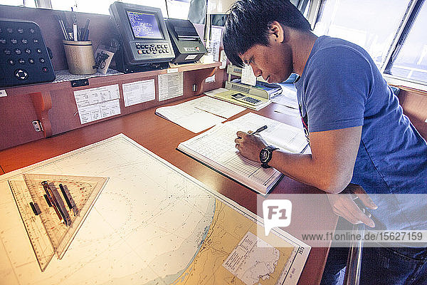 Ein Offizier auf einem Containerschiff prüft vor der Durchfahrt durch den Golf von Aden Karten und Pläne.