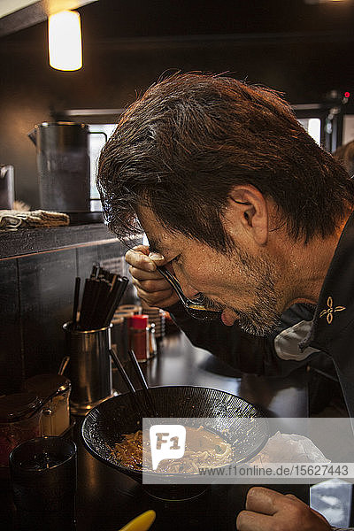 Seitenansicht eines Mannes  der Ramen isst  Tokio  Japan