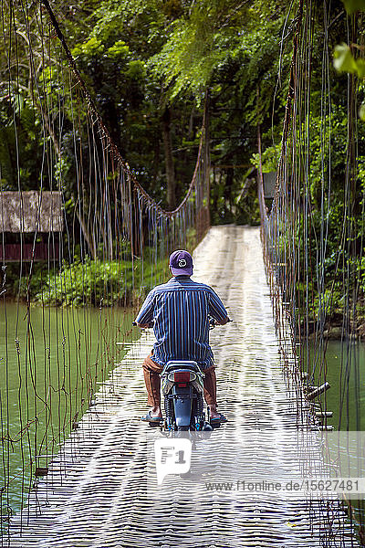 Mann fährt Motorrad auf einer Seilbrücke