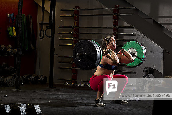 Ein Crossfit-Sportler trainiert mit schweren Gewichten an einer Langhantel in einem düsteren Fitnessstudio in San Diego  Kalifornien.