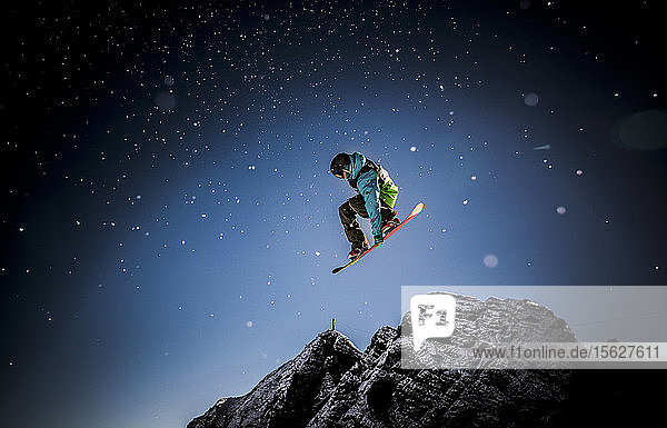 A snowboarder leaping into the air on the Dachstein-Glacier in Austria  leaving a trail of snow behind him.