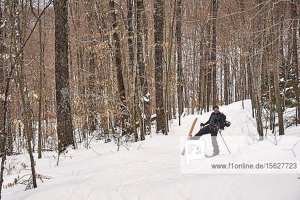 A man skinning his way through the Vermont backcountry on a splitboard.