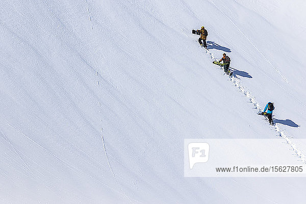 Snowboarder wandern in einer Gruppe auf eine saubere Schneedecke auf dem Weg zu ihren Lines