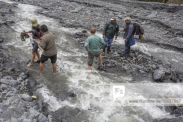 Foto von fünf Wanderern bei der Flussüberquerung im peruanischen Nebelwald