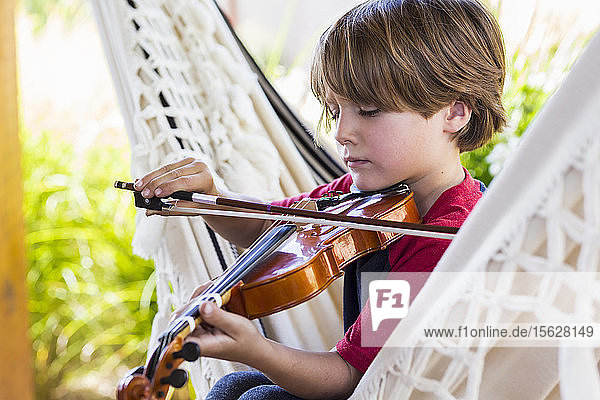 Sechsjähriger Junge spielt Geige im Garten