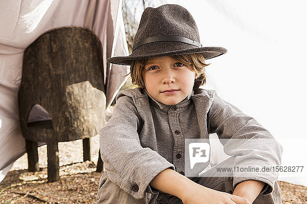 Sechsjähriger Junge spielt in einem Außenzelt aus Laken