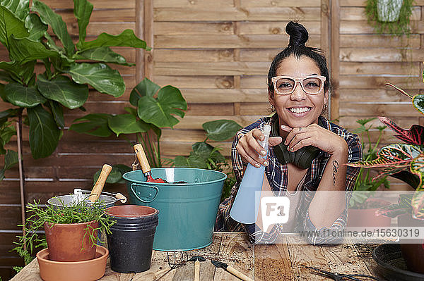 Porträt einer lächelnden jungen Frau bei der Gartenarbeit auf ihrer Terrasse