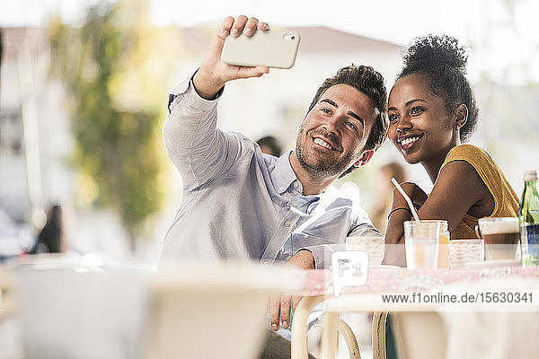 Glückliches junges Paar beim Selfie in einem Straßencafé