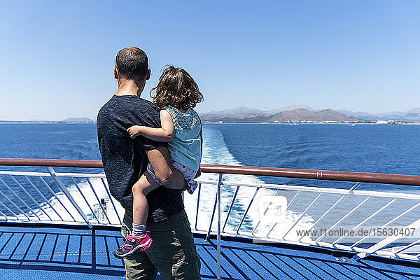 Rückansicht eines Vaters und einer kleinen Tochter zusammen auf dem Deck eines Schiffes mit Blick in die Ferne  Mallorca  Spanien