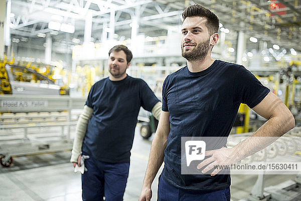 Zwei selbstbewusste Kollegen machen eine Pause in einer modernen Fabrik