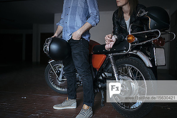 Ehepaar mit Oldtimer-Motorrad in der Garage geparkt