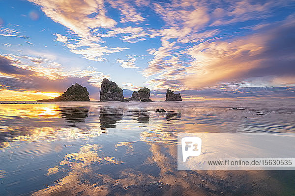 Neuseeland  Südinsel  Wolken und Meeresschornsteine spiegeln sich im glänzenden Küstenwasser des Motukiekie Beach bei Sonnenuntergang