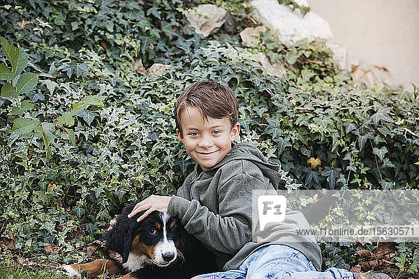 Boy playing with his Bernese mountain dog in the garden