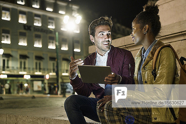 Junges Paar benutzt digitales Tablet in der Stadt bei Nacht  Lissabon  Portugal