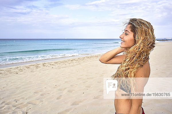 Lächelnde junge Frau steht am Strand