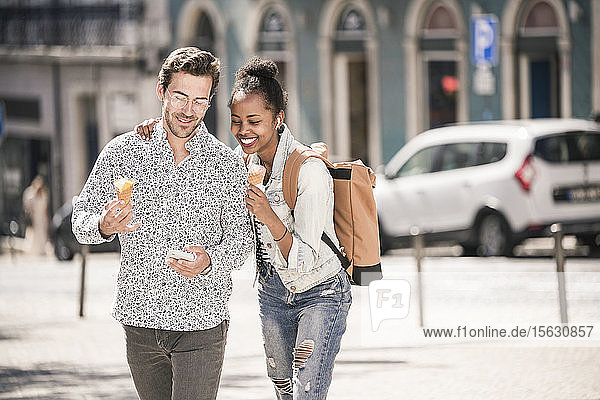 Happy young couple with ice cream and mobile phone in the city on the go  Lisbon  Portugal