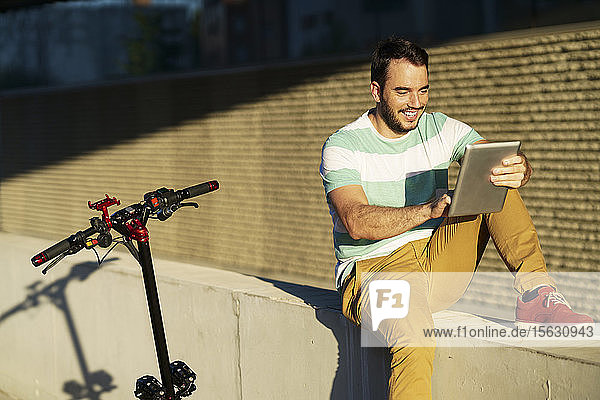 Porträt eines lächelnden Mannes mit Elektroroller mit digitalem Tablet