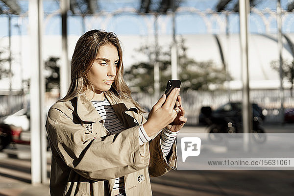 Junge blonde Frau  die ein Smartphone benutzt und ein Selfie