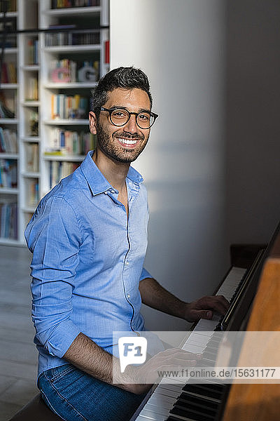 Portrait of happy young man playing piano at home