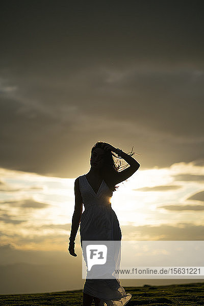 Junge Frau trägt weißes Kleid bei Sonnenuntergang