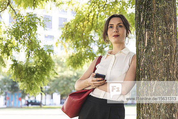 Junge Geschäftsfrau mit Handy in einem Park