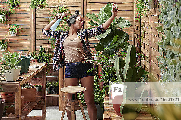 Glückliche junge Frau  die bei der Gartenarbeit auf ihrer Terrasse tanzt