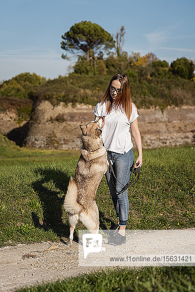 Young woman teaching her dog in nature