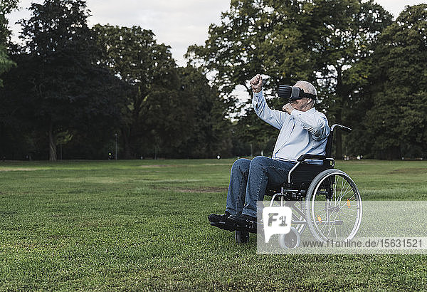 Älterer Mann sitzt im Rollstuhl und benutzt eine Virtual-Reality-Brille