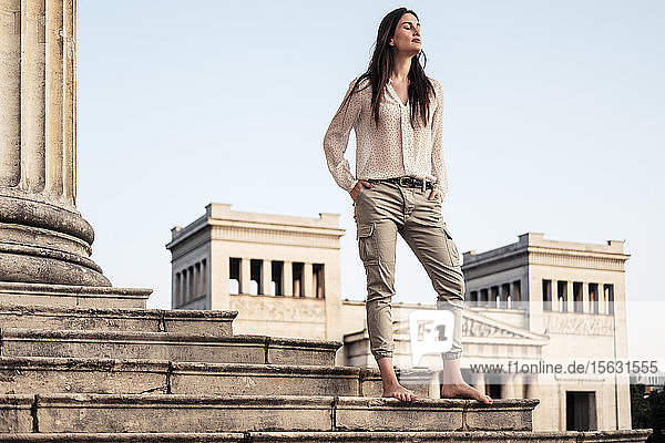 Barfüßige junge Frau steht auf der Treppe am Königsplatz und entspannt sich  München  Deutschland