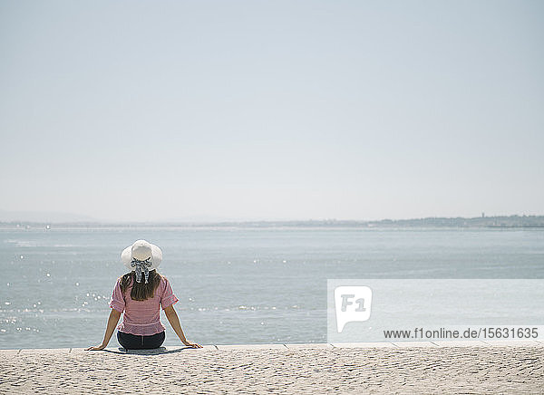 Rückansicht einer an der Küste sitzenden Frau  Lissabon  Portugal