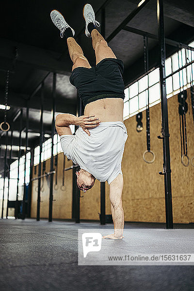 Young man doing a handstand during cross training