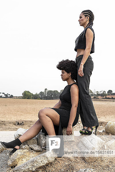 Zwei schwarz gekleidete Frauen auf einem Trümmerhaufen in der Ferne