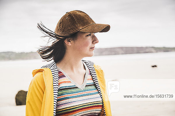 Porträt einer jungen Frau in gelber Regenjacke am Strand  Bretagne  Frankreich
