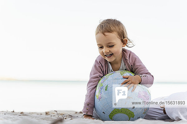 Porträt eines glücklichen kleinen Mädchens beim Spielen mit dem Earth-Beachball