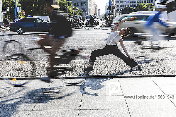 Junge Geschäftsfrau praktiziert Yoga in der Stadt zur Hauptverkehrszeit  Berlin  Deutschland