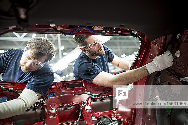 Zwei Kollegen arbeiten an der Karosserie in einer modernen Autofabrik
