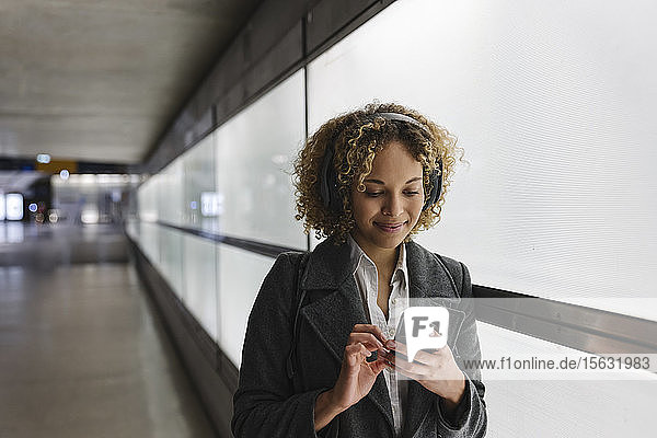 Lächelnde Frau mit Kopfhörer und Smartphone