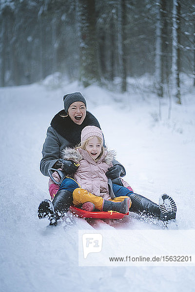 Portrait of mature woman sledging together with her daughter