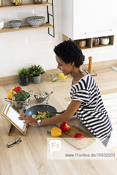 Young woman using tablet cooking in kitchen at home