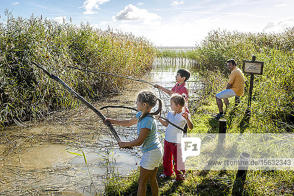 Children playing with wood sticks at water course  Darss  Mecklenburg-Western Pomerania  Germany