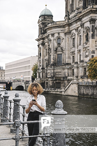 Tourist woman using smartphone in the city at Spree river  Berlin  Germany
