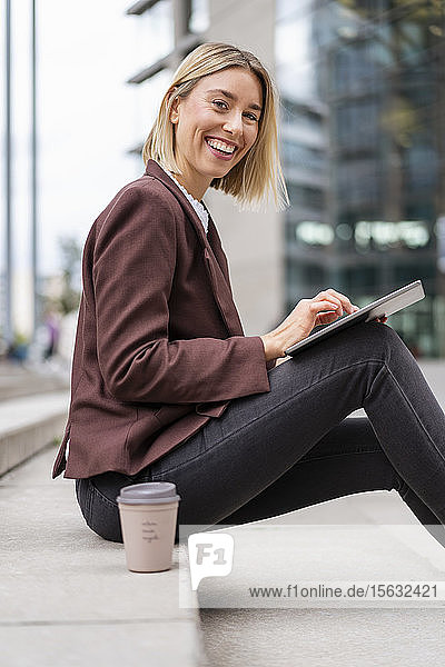 Porträt einer glücklichen jungen Geschäftsfrau mit Tablette in der Stadt