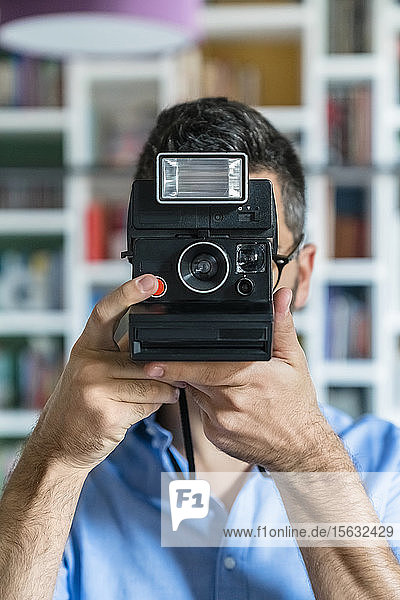 Junger Mann fotografiert mit Sofortbildkamera