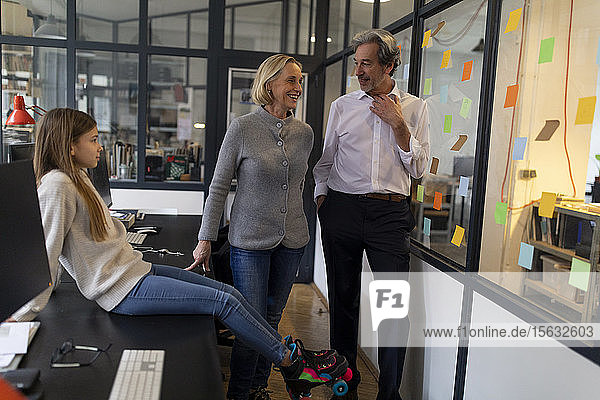 Businessman and businesswoman with girl with roller skates in office