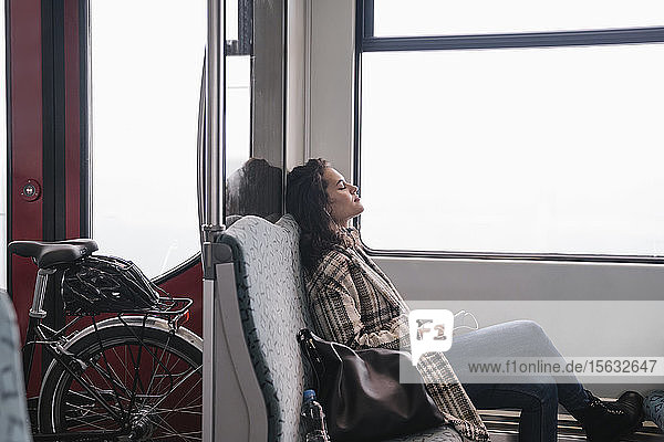 Junge Frau mit geschlossenen Augen entspannt sich in einer U-Bahn