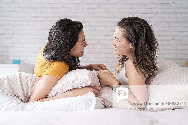 Glückliches anhängliches lesbisches Paar im Bett liegend