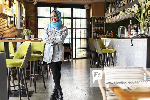 Junge Frau mit türkisfarbenem Hidschab in einem Cafe