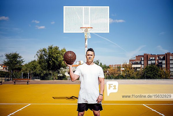 Basketballspieler  der mit dem Ball vor der Kamera posiert