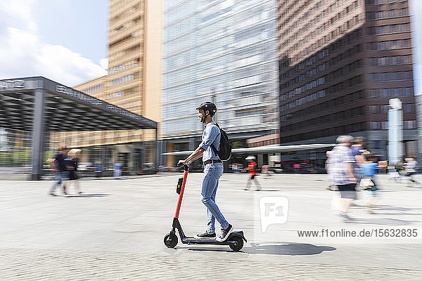 Geschäftsmann auf dem E-Scooter auf dem Bürgersteig in der Stadt  Berlin  Deutschland