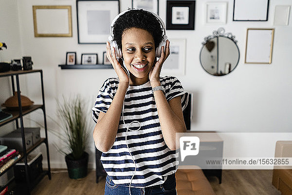 Happy young woman listening to music with headphones at home